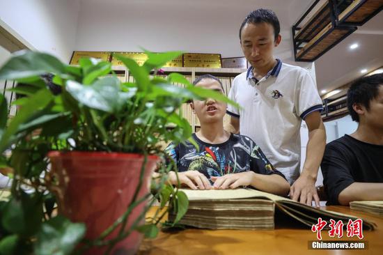 图为9月7日，贵州省惠水县，罗强在指导学生阅读盲文版医学书籍。
