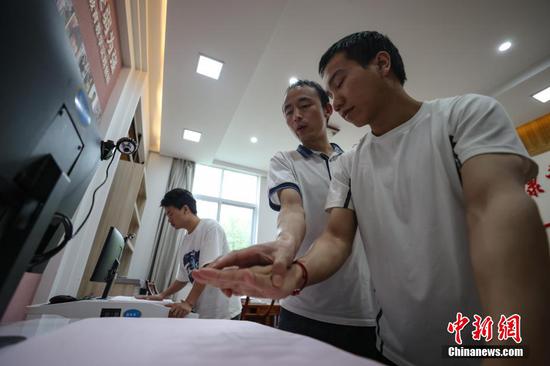 9月7日，贵州省惠水县，罗强（中）在指导学生使用手法仪测评手法。
