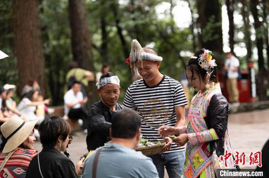 游客在贵州省从江县丙妹镇岜沙苗寨参与婚俗互动。吴德军 摄