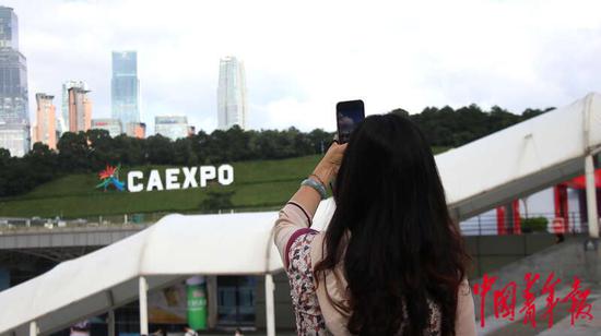 9月16日,广西南宁国际会展中心,一名东博会参展商正对着远处“CAEXPO”的标识拍照留念。中青报·中青网见习记者 王军利/摄 9月16日,广西南宁国际会展中心,一名东博会参展商正对着远处“CAEXPO”的标识拍照留念。中青报·中青网见习记者 王军利/摄