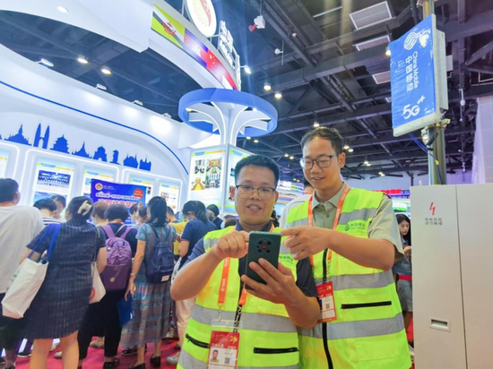 广西移动通信专家杨天荣（左）与伙伴一起运用手机在场馆内监测5G皮基站的运行情况。