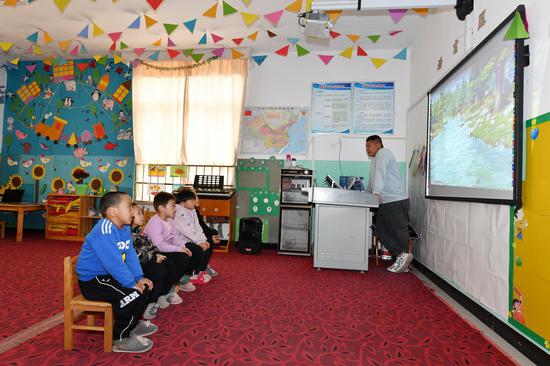 斯木哈纳村幼儿园孩子通过“班班通”看动画片。石怀平 摄