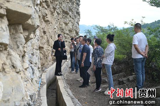 图为9月20日媒体嘉宾在贵州省毕节市七星关区七星关区生机镇高流大渠上听解说员讲“绝壁天渠”的历史。唐哲 摄