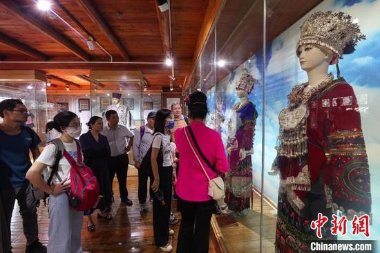 游客在西江千户苗寨景区博物馆观看苗族服饰展。中新网记者 瞿宏伦 摄