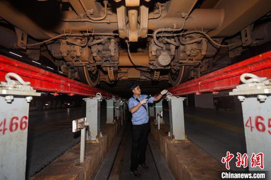图为机械师在车底检修设备。中新网记者 瞿宏伦 摄