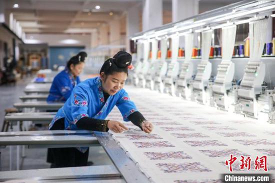 图为工人在贵州一旅游商品开发有限公司机绣车间生产苗绣产品。磨桂宾 摄
