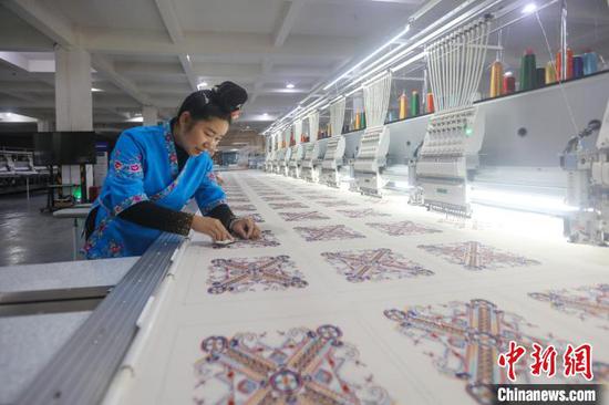 图为工人在贵州一旅游商品开发有限公司机绣车间生产苗绣产品。磨桂宾 摄
