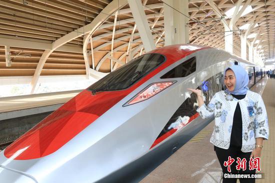 图为乘客在列车前。记者从中国国家铁路集团有限公司（以下简称国铁集团）获悉，北京时间10月17日16时35分，G1137次动车组列车从印尼雅加达哈利姆车站开出，雅加达至万隆高速铁路正式开通运营，列车最高运营时速350公里，两地最快46分钟可达，这标志着印尼迈入高铁时代，中印尼共建“一带一路”取得重大标志性成果。图为乘客在列车前与列车合影。中新社记者 李志全 摄