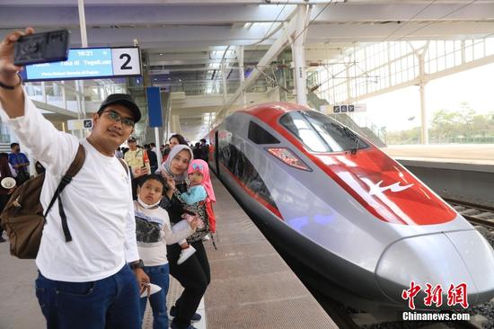 当地时间10月17日，印尼万隆德卡鲁尔站，印尼一家四口在列车前拍照合影。当日，印尼雅加达至万隆高速铁路正式开通运营。这标志着印尼迈入高铁时代，中印尼共建“一带一路”取得重大标志性成果。中新社记者 李志全 摄