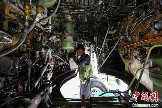 11月8日，贵州省贵阳市，一名机务在飞机轮舱部进行液压油添加工作。中新网记者 瞿宏伦 摄