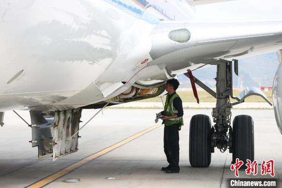 11月8日，贵州省贵阳市，一名机务在飞机空调组件处检查氮气发生器。中新网记者 瞿宏伦 摄