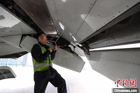 11月8日，贵州省贵阳市，一名机务在飞机机翼下检查后缘襟翼。中新网记者 瞿宏伦 摄