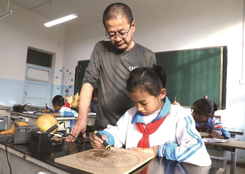 ⑥张镇藩为昌吉市第十三小学的学生教授烙画技艺。

