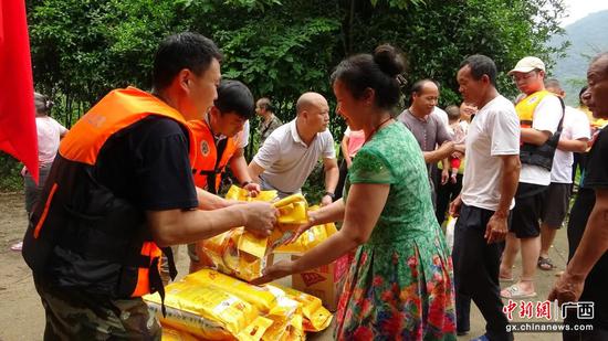 图为应急救援人员为受灾群众发放物资。