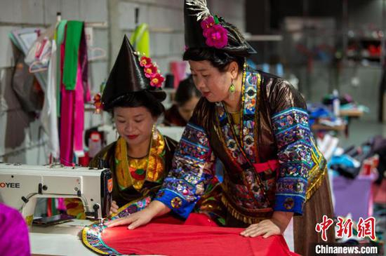 11月21日，韦祖英(右)在公司的制衣车间指导员工缝制衣服。吴德军 摄