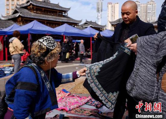 图为游客在绣里淘非遗集市上挑选心仪的民族服饰。周燕玲 摄