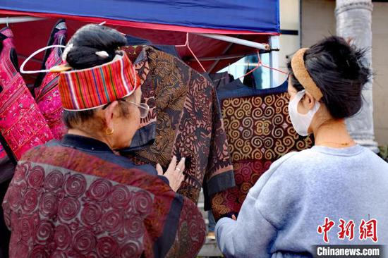 图为绣娘在集市为游客介绍民族服饰。周燕玲摄