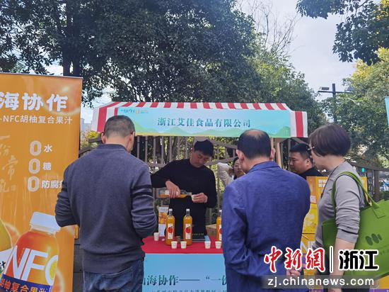 浙江艾佳食品有限公司的展位前，围满了前来品尝NFC胡柚复合果汁的市民。陈倩 供图