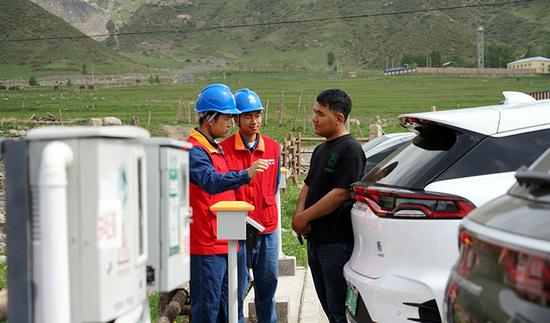 在阿克苏温宿县塔村旅游景区，国网阿克苏供电公司员工向游客介绍共享充电设施。（樊洁 摄）