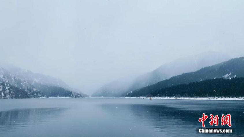 冬日时节，一场雪悄然在新疆天山天池景区落下。乌蒙蒙的天空下，湖水与两岸青山交相呼应，波光粼粼的湖面映照着皑皑白雪，游客们宛如置身冰雪世界。 陈传松 摄