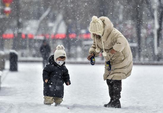 12月11日，新疆乌鲁木齐市迎来降雪。图为市民带着孩子在雪中玩耍。中新社记者 刘新 摄