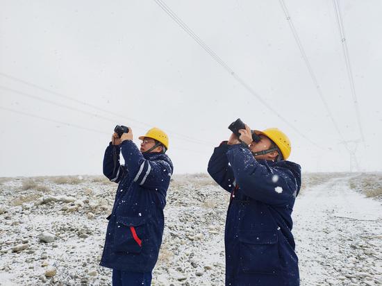 12月14日，新疆送变电公司员工正在巡视750千伏库巴一线370号塔金具及导地线覆冰情况。杨志喜 摄