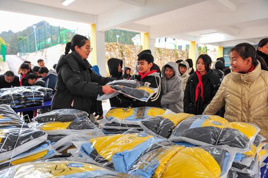 在贵州省黔东南苗族侗族自治州从江县贯洞镇第二小学，一名老师在给学生发放新校服。