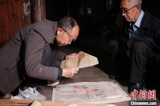 图为锦屏县档案馆原馆长王宗勋(左)在姜绍明老人家里查看收藏的文书。周燕玲 摄