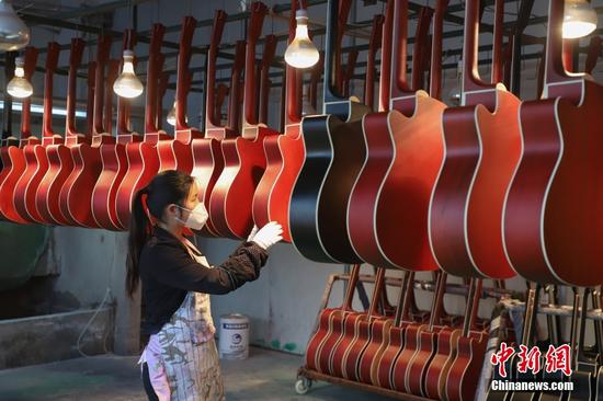 正安也因此成为了名副其实的吉他“世界工厂”。图为工人在整理喷漆后的吉他。
中新社记者 瞿宏伦 摄