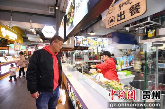 12月31日，一市民在贵阳市南明区青云路步行街品尝贵州特色美食。