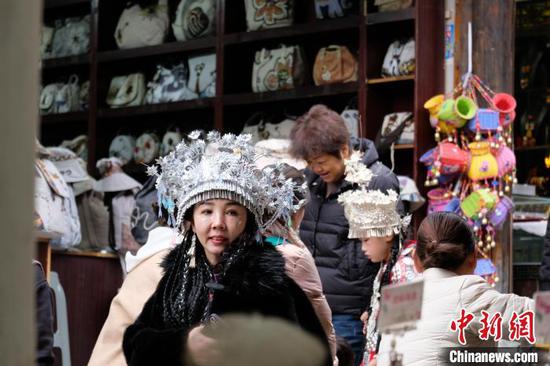 戴着民族头饰的游客在贵阳青岩古镇景区游览。中新网记者石小杰 摄