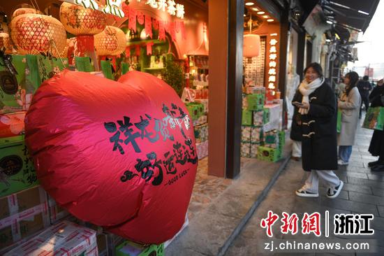 商家以爱心气球和龙元素吉祥语吸引游人。中新社记者 王刚 摄