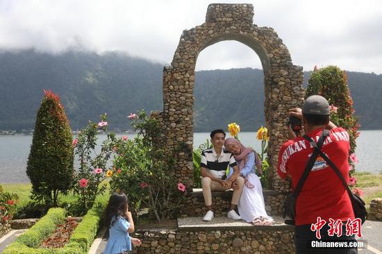 当地时间1月13日，游客在印度尼西亚巴厘岛水神庙景区拍照。中新社记者 李志全 摄