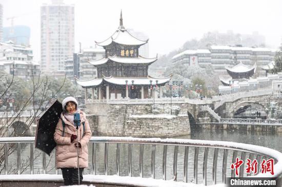 市民以贵阳市甲秀楼雪景为背景拍照。中新网记者 瞿宏伦 摄