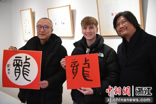 外籍友人（中）和现场嘉宾书写“龙”字并展示。中新社记者 王刚 摄