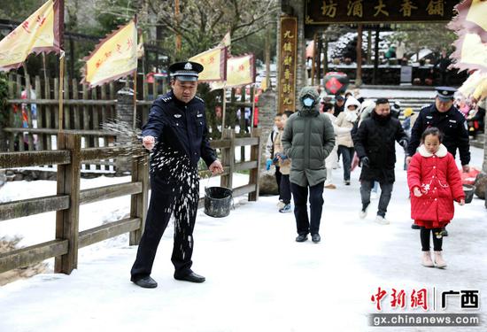 图为民警在景区结冰湿滑的路面上撒盐，消除安全隐患。