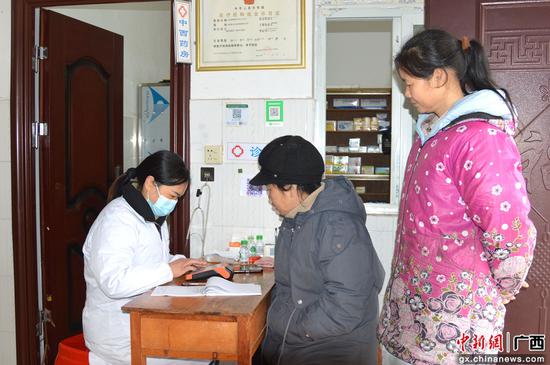 图为骆春燕在村卫生室为村民检查身体健康情况。韦明崧 摄