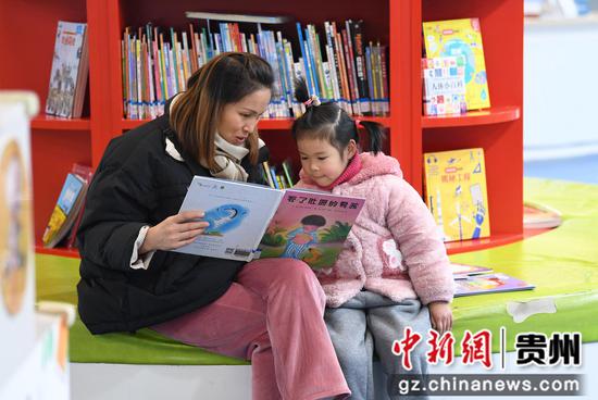 1月26日，在贵阳市南明区图书馆内的少儿阅读区，一名小学生的家人的陪同下阅读儿童图书。