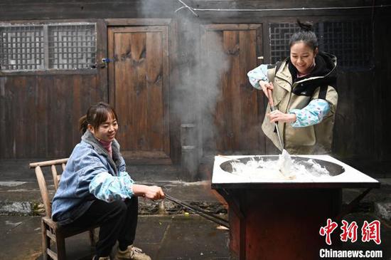 图为村民在熬制米浆。谢慧芳 摄