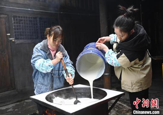 图为村民将制作米豆腐的米浆倒入锅中。谢慧芳 摄