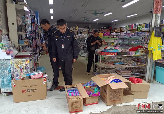 图为执法人员查处贵港某小学周边文具店售卖烟花爆竹。