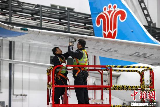 图为两名机务在飞机机翼下检修。中新网记者 瞿宏伦 摄