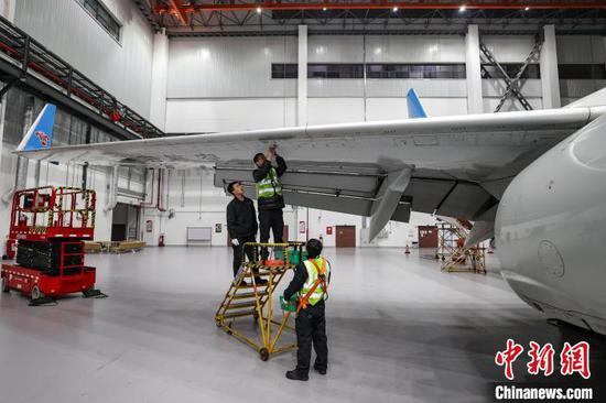 图为两名机务在飞机机翼下检修。中新网记者 瞿宏伦 摄