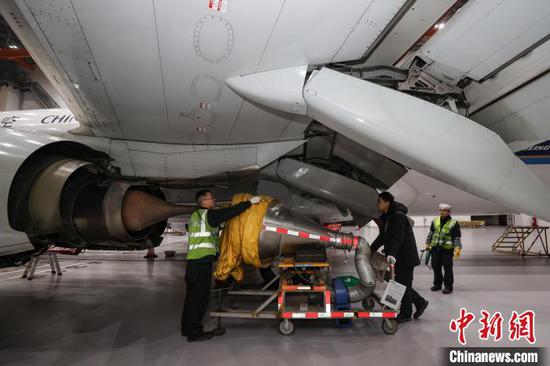 图为机务人员在安装飞机发动机降温设备。中新网记者 瞿宏伦 摄