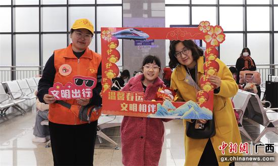图为：桂林火车站青年志愿邀请旅客与文明出行打卡“同框”。（郑长贤 摄）