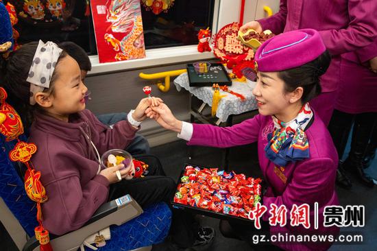 图为乘务员给小旅客送上糖果和年糕。章汝慧 摄