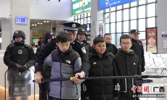 桂林站派出所民警邀请旅客亲身体验操作维稳装备。郑长贤 摄