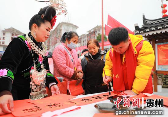 2023年2月2日，在贵州省黔东南苗族侗族自治州雷山县龙头街道移民安置点，书法志愿者为居民义务写春联。