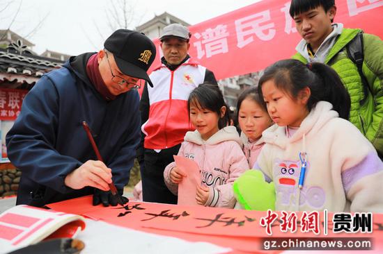 2023年2月2日，在贵州省黔东南苗族侗族自治州雷山县龙头街道移民安置点，书法志愿者为居民义务写春联。