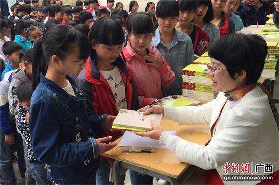 图为丁灯到广西隆林县平班镇中心小学给留守儿童捐赠她的著作《西部梦》和《丁灯诗集》。 被访者供图